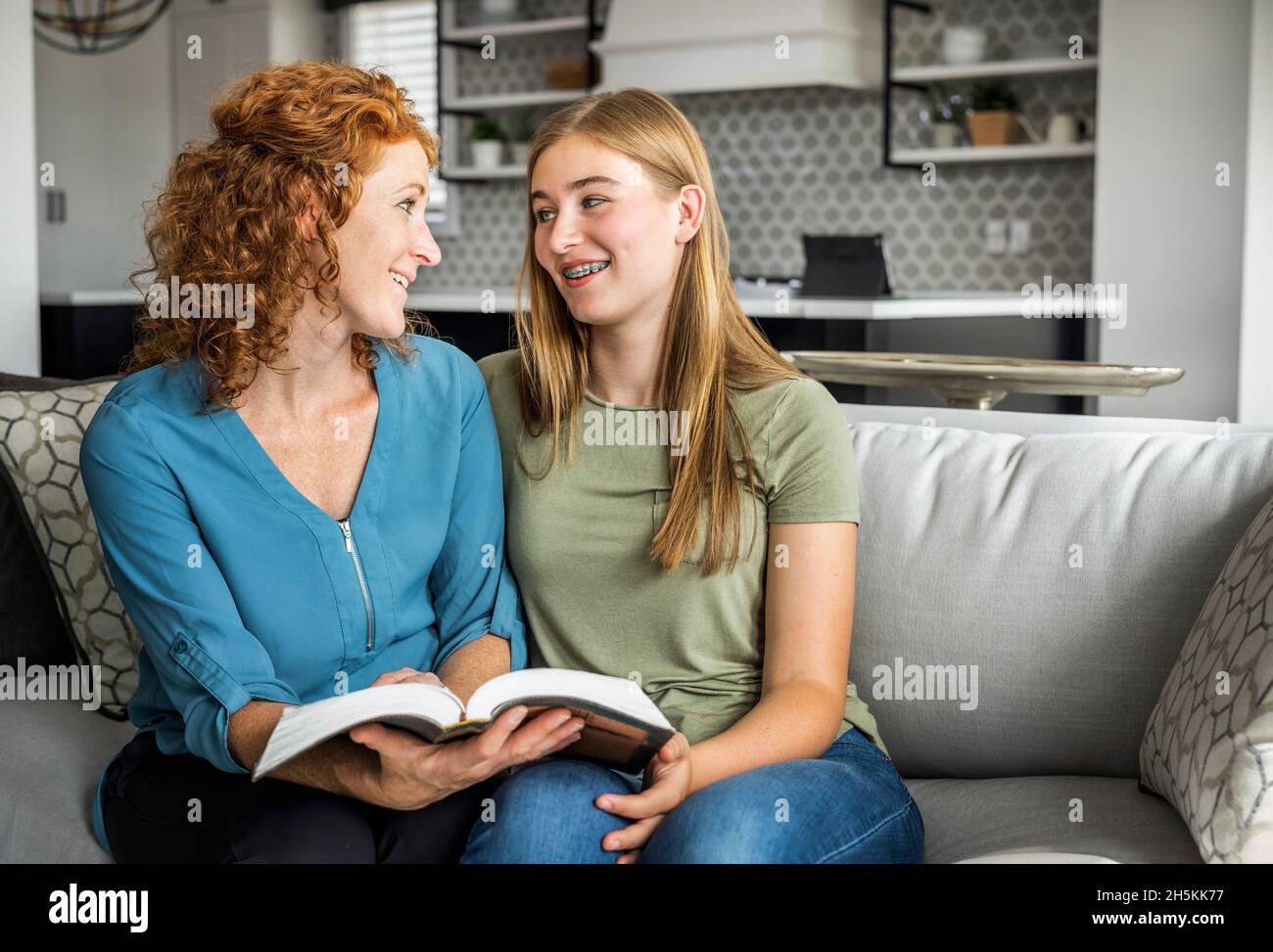 Mutter und Tochter im Teenageralter sitzen zu Hause auf einer Couch und lesen gemeinsam die Bibel; Edmonton, Alberta, Kanada Stockfoto