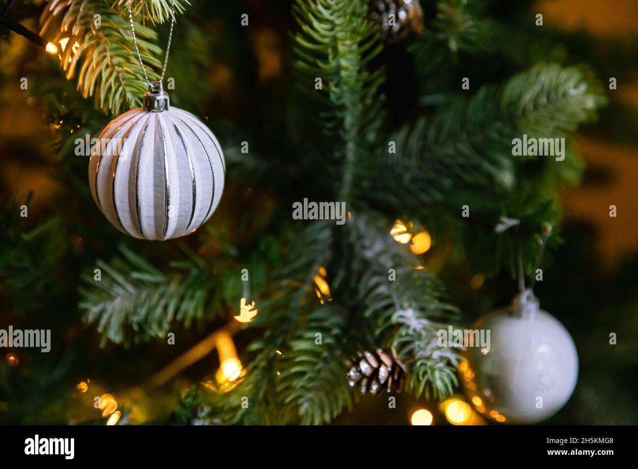 Klassischer Weihnachtsbaum mit Weihnachtsschmuck. Weihnachtsbaum mit wite und silbernen Dekorationen, Ornamente Spielzeug und Ball. Moderne Einrichtung im klassischen Stil Stockfoto