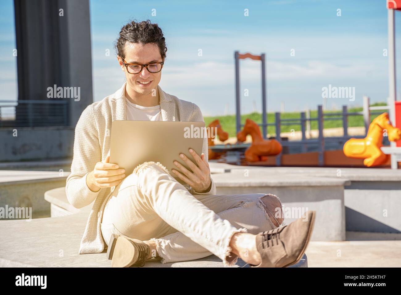 Junger Mann, der von zu Hause aus im Stadtleben auf einem Laptop im Freien arbeitet Stockfoto