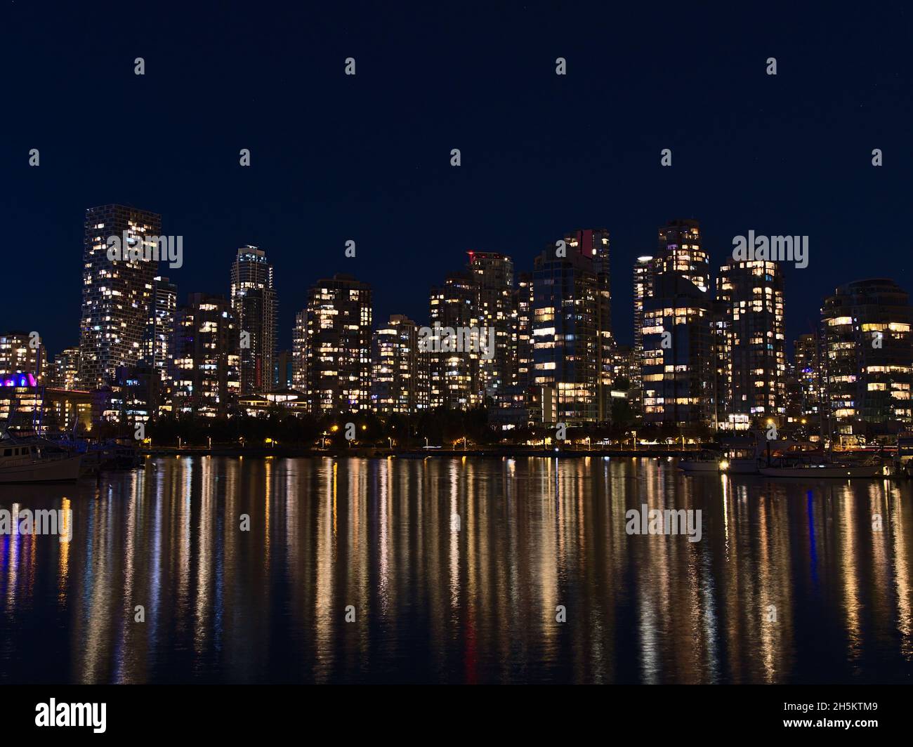 Nachtansicht der Skyline von Vancouver, British Columbia, Kanada in der Innenstadt mit Lichtern von beleuchteten Hochhäusern, die sich im glatten Wasser spiegeln. Stockfoto