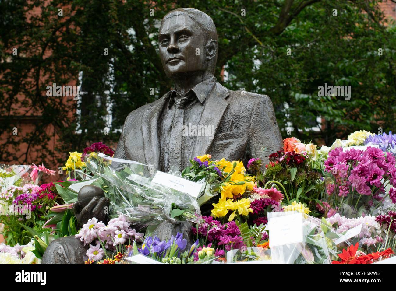 Alan Turing Statue umgeben von Blumen zu seinem Geburtstag. Sackville Gardens, Manchester, Großbritannien Stockfoto