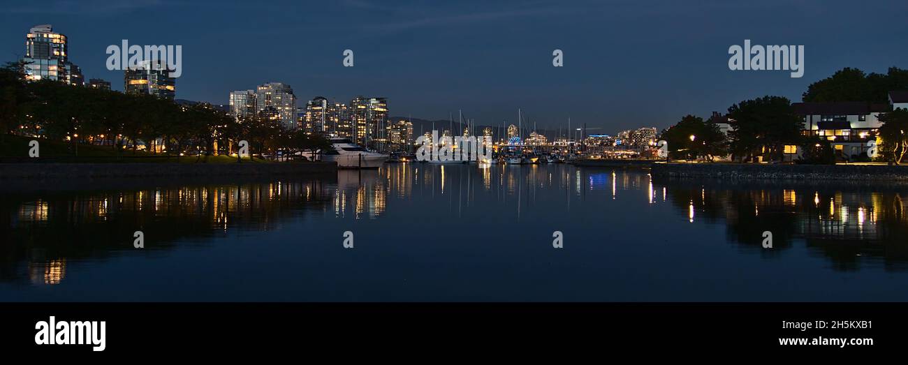 Panoramablick auf die Bucht von False Creek mit Yachthafen, Booten, Promenade und der beleuchteten Skyline von Vancouver im Hintergrund in Kanada. Stockfoto