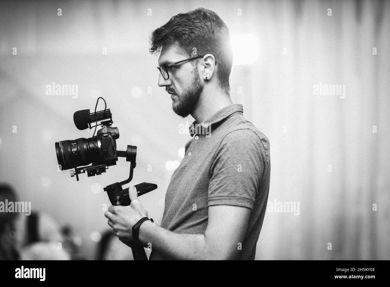 Graustufen eines kaukasischen Mannes, der eine professionelle Kamera hält und fotografiert Stockfoto