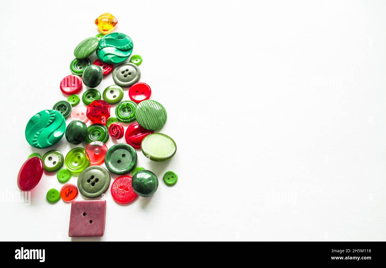 Ein Weihnachtsbaum aus grünen, roten Knöpfen. Weißer Hintergrund, Kopierraum. Kreatives Weihnachtskonzept. Stockfoto