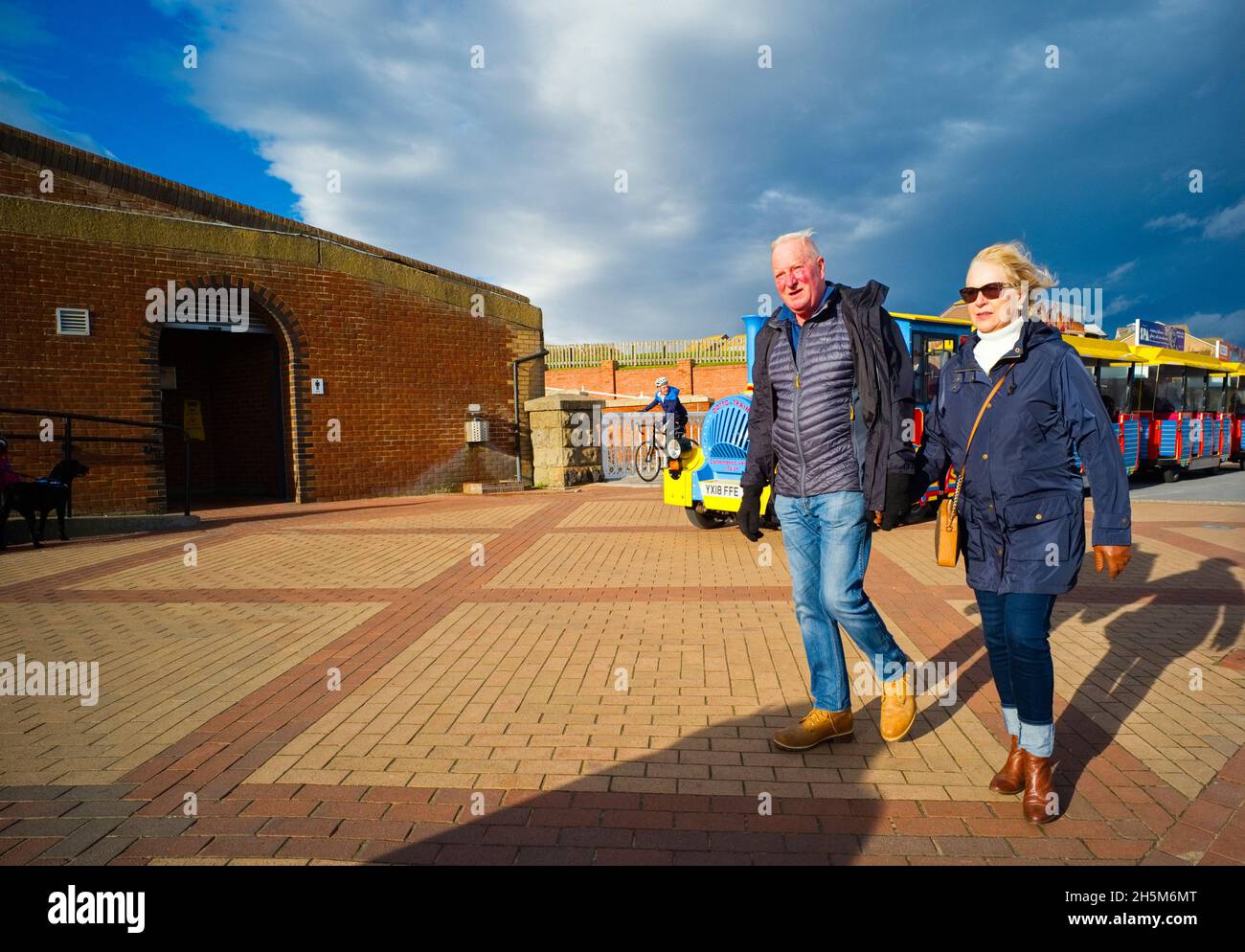Ein älteres Paar, das am Meer in Bridlington, East Riding, in den Wind läuft Stockfoto