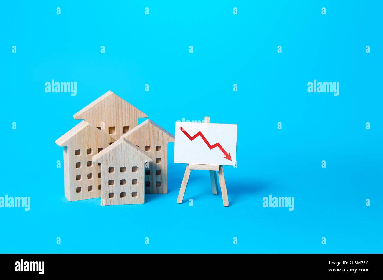 Wohngebäude und Pfeil-nach-unten-Diagramm auf Staffelei. Niedriger Wert der Immobilie, niedriger Preis. Rückgang des Immobilienmarktes. Niedrigere Hypothekenzinsen. Sinkende Pr Stockfoto