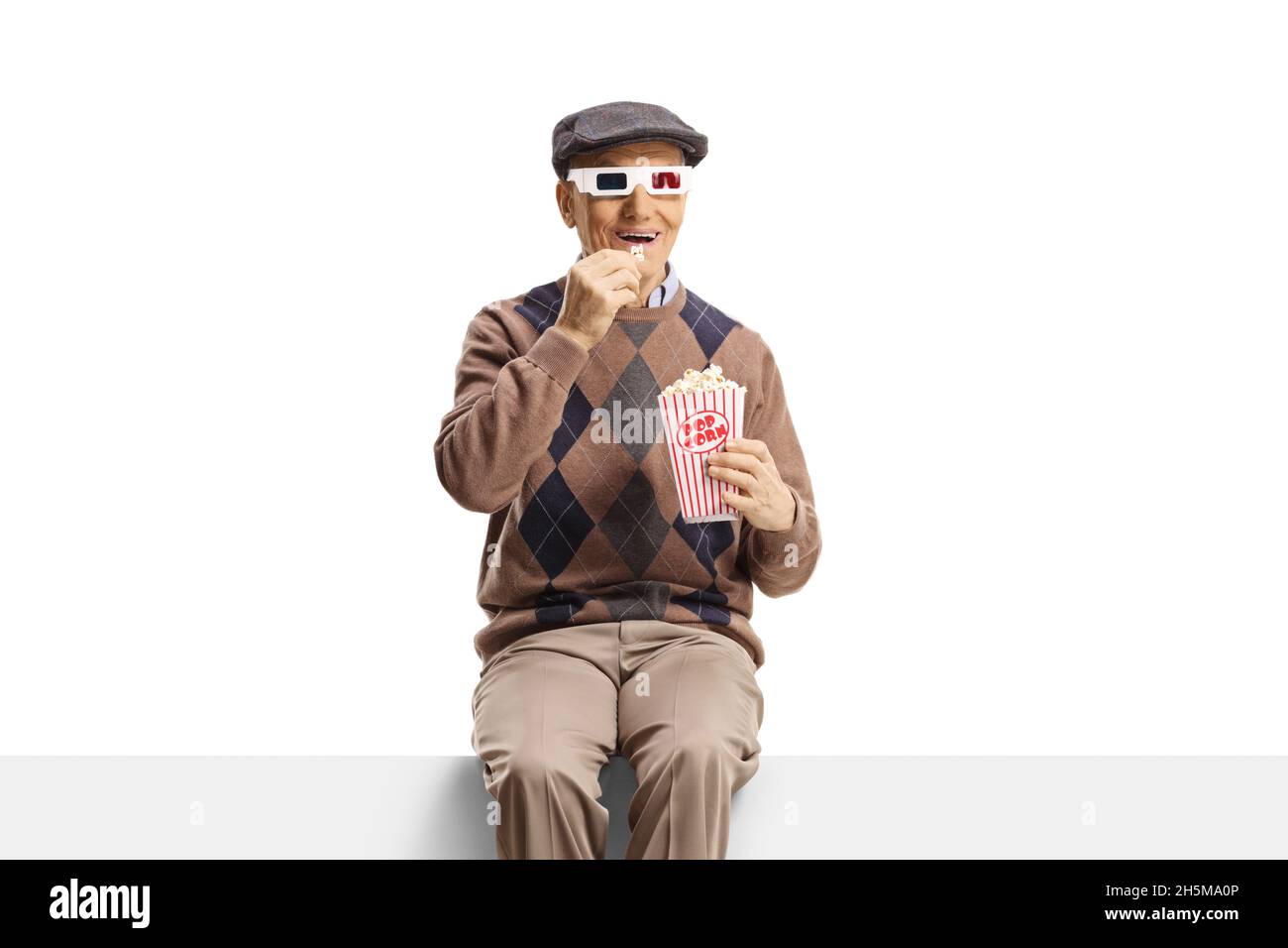 Älterer Mann, der auf einem Panel sitzt, auf dem Popcorn und 3d-Filmbrillen auf weißem Hintergrund isoliert sind Stockfoto