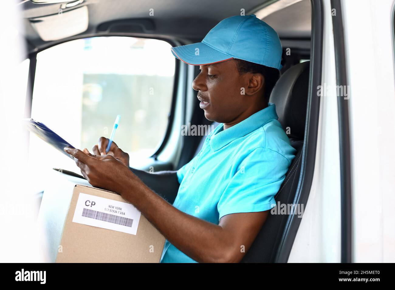 Afroamerikanischer Kurier des Lieferunternehmens, der im Auto sitzt Stockfoto