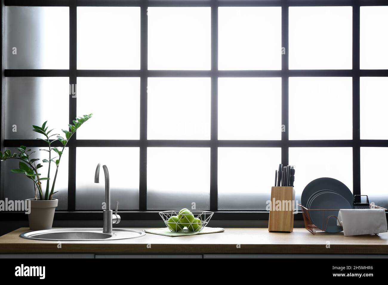 Schüssel mit grünen Äpfeln auf der Küchentheke neben dem großen Fenster Stockfoto