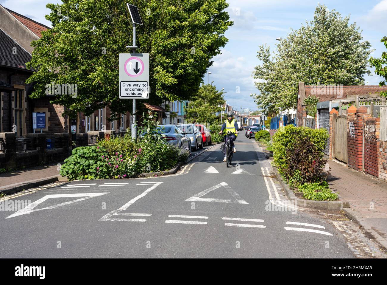 Eine verkehrsberuhende Prise Point mit Straßenbäumen und Pflanzungen reduziert und verlangsamt den Verkehr vor einer Grundschule in Southville, Bristol. Stockfoto