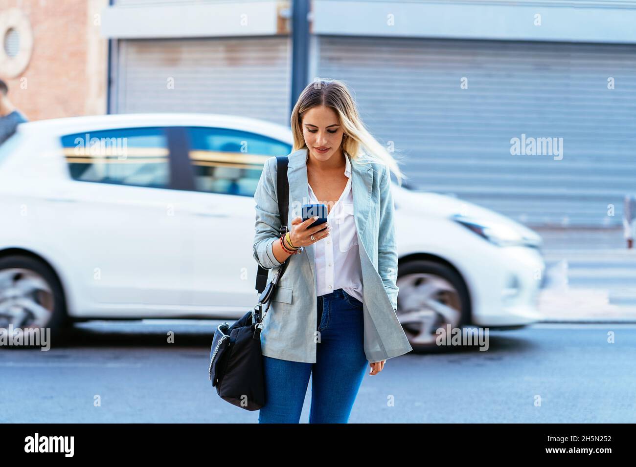Lächelnde Geschäftsfrau beim Stöbern auf dem Smartphone in der Stadt Stockfoto