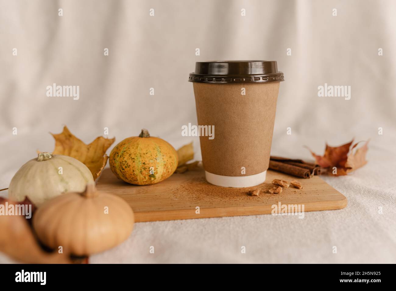 Kaffee Take Away Tasse im Herbst Kürbis aufgestellt. Kürbis-Latte mit Schlagsahne und frischem Zimt würzen. Kaffee zum trinken Stockfoto