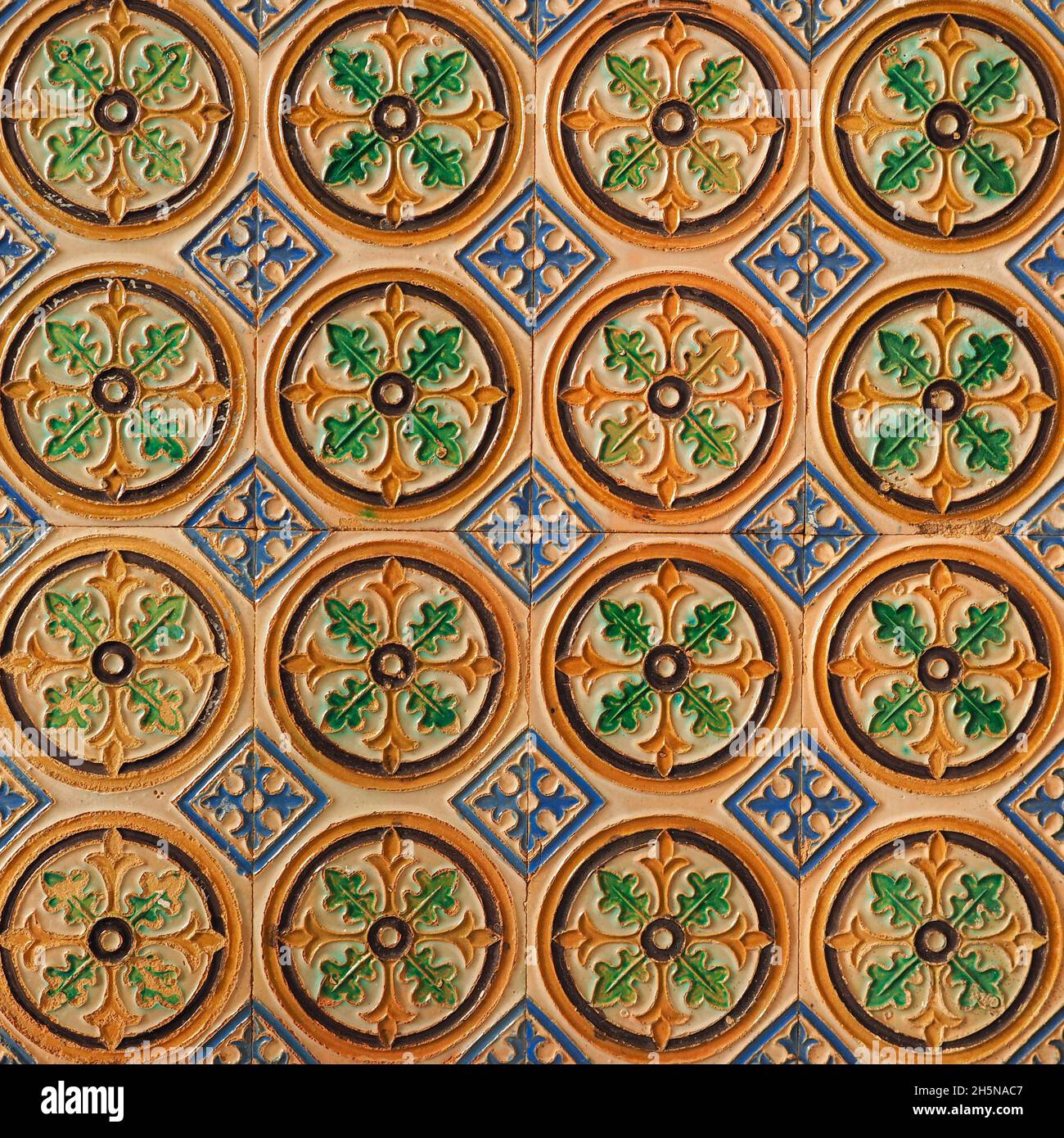 Fragment der Gebäudewand mit glasierten keramischen Fliesen, geprägter Vintage Mudejar, Nahaufnahme. Traditionelle, reich verzierte spanische Architektur. Abstrakter Hintergrund. Stockfoto