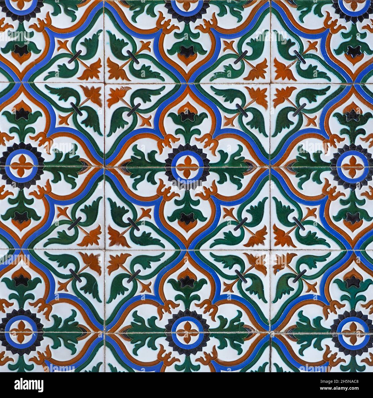Fragment der Gebäudewand mit glasierten keramischen Fliesen, geprägter Vintage Mudejar, Nahaufnahme. Traditionelle, reich verzierte spanische Architektur. Abstrakter Hintergrund. Stockfoto