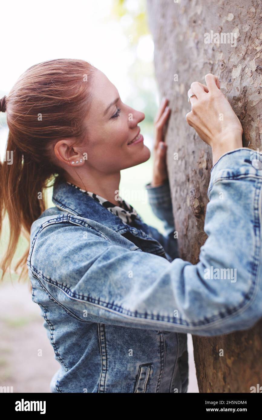 Junge Rotschopf kaukasische Frau Gravur Liebe Zeichen in Baum in der Natur im Herbst, vertikal Stockfoto