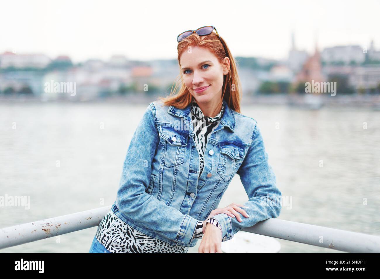 Glückliche junge Rotschopf kaukasische Frau am Flussufer Blick in die Kamera Stockfoto