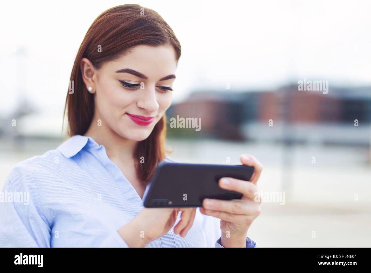 Junge Rotschopf kaukasischen weißen Kragen Arbeiter Messaging auf Handy im Freien Stockfoto