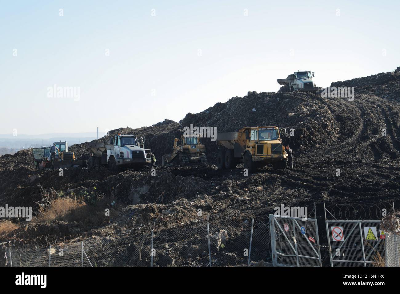 Lastwagen und Bagger auf der Deponie Hrybovytchi, die unter Rückgewinnung (künstliche Wiederherstellung der Bodenfruchtbarkeit und Vegetation nach vom Menschen verursachte Störung der Natur) gesehen. Der einzige legale Ort für die Müllabfuhr aus Lemberg und den umliegenden Dörfern. Es ist seit 1958 in Betrieb in der Nähe des Dorfes Velyki Hrybovychi. Die Deponiefläche beträgt über 38 Hektar. Am 28. Mai 2016 brach auf dem Gebiet der Hrybovyzja-Deponie ein großes Feuer aus, das einen Zusammenbruch von festen Abfällen verursachte, bei dem drei Helfer unter den Trümmern starben. Stockfoto