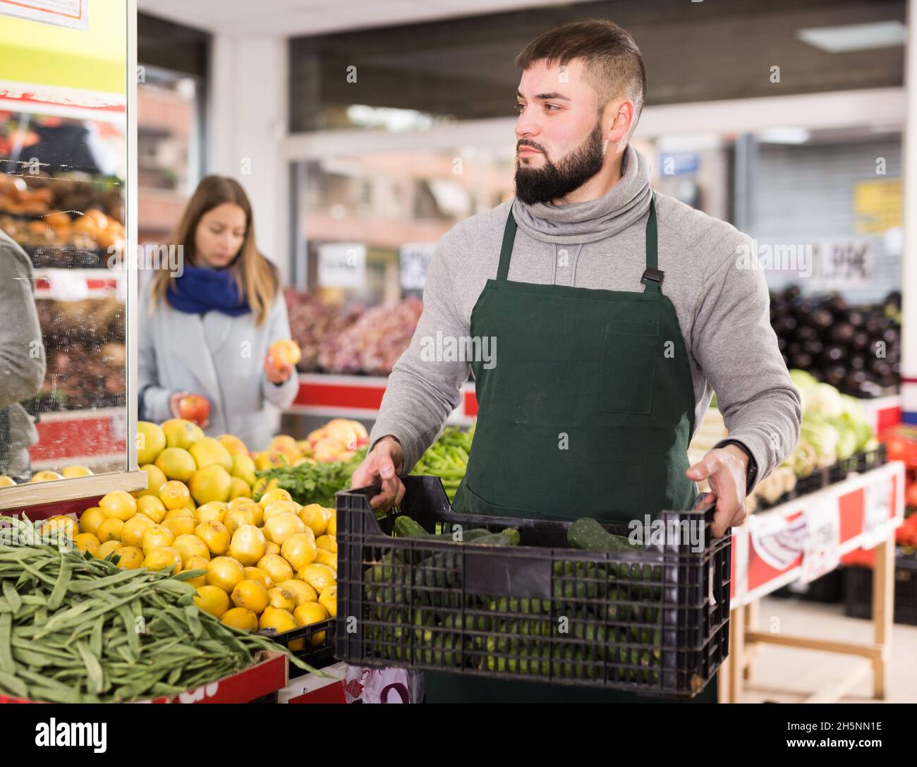 Positive Verkäufer in Schürze arbeiten in Gemüsemarkt Stockfoto