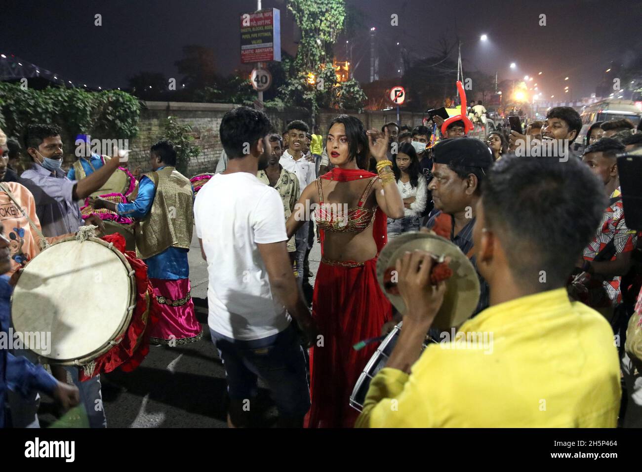 Kalkutta, Indien. November 2021. Ein indischer Eunauch tanzt, während sich eine hinduistische Anhängerin während des Chhath-Festivals auf dem Boden niederlässt, während sie in Richtung des Ganges in Kalkutta weitergeht. 'Chhath' bezeichnet die Zahl 'Six' und das Fest beginnt am sechsten Tag des Hindu-Monats 'Kartik' im Hindu-Mondkalender, entsprechend Ende Oktober und Mitte November, je nach Jahr. Es ist eines der heiligsten Festivals für Biharis und erstreckt sich über vier Tage. (Foto: Dibakar Roy/Pacific Press) Quelle: Pacific Press Media Production Corp./Alamy Live News Stockfoto