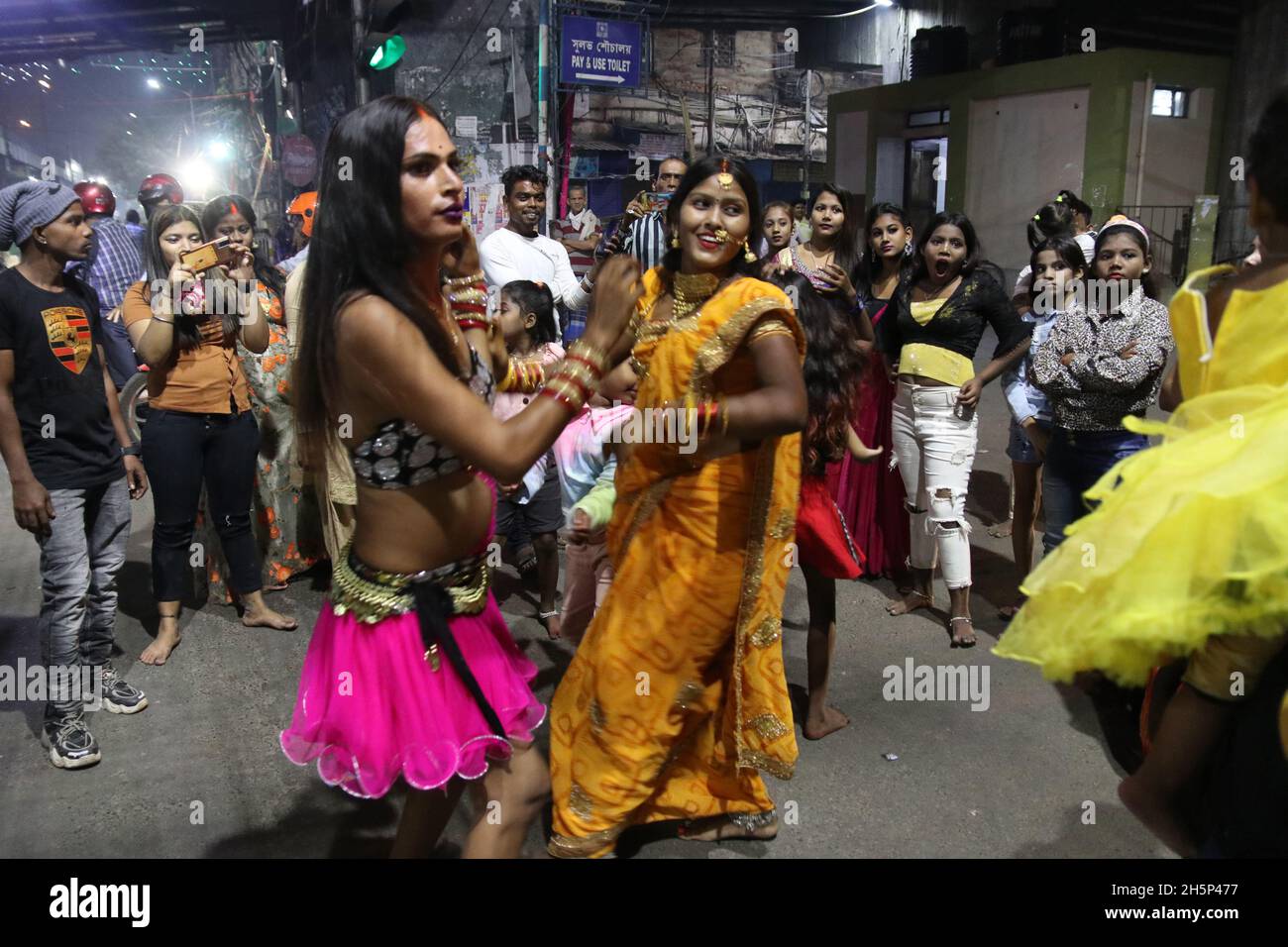 Kalkutta, Indien. November 2021. Ein indischer Eunauch tanzt, während sich eine hinduistische Anhängerin während des Chhath-Festivals auf dem Boden niederlässt, während sie in Richtung des Ganges in Kalkutta weitergeht. 'Chhath' bezeichnet die Zahl 'Six' und das Fest beginnt am sechsten Tag des Hindu-Monats 'Kartik' im Hindu-Mondkalender, entsprechend Ende Oktober und Mitte November, je nach Jahr. Es ist eines der heiligsten Festivals für Biharis und erstreckt sich über vier Tage. (Foto: Dibakar Roy/Pacific Press) Quelle: Pacific Press Media Production Corp./Alamy Live News Stockfoto