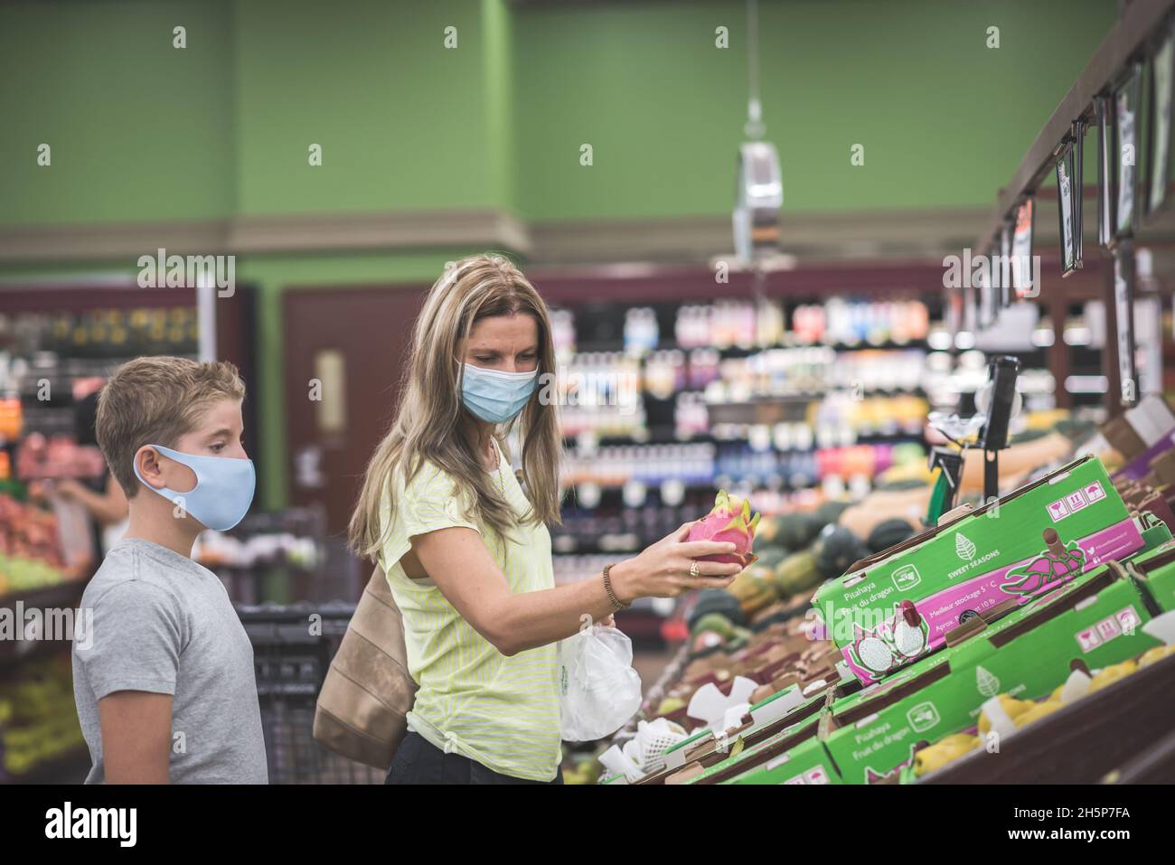 Chicago, IL- 21. August 2021:Mutter und Kind tragen Masken Einkaufen im Supermarkt nur für redaktionelle Zwecke Familie trägt Masken beim Pflücken von Früchten im Supe Stockfoto