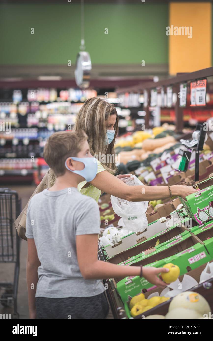 Chicago, IL- 21. August 2021:Mutter und Kind tragen Masken Einkaufen im Supermarkt nur für redaktionelle Zwecke Familie trägt Masken beim Pflücken von Früchten im Supe Stockfoto