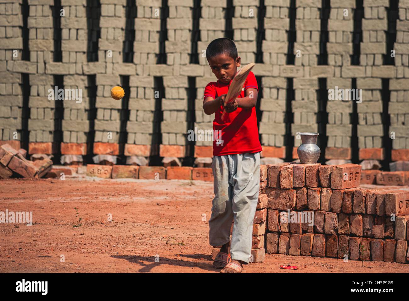 Ein Junge spielt Cricket auf dem Ziegelfeld Stockfoto