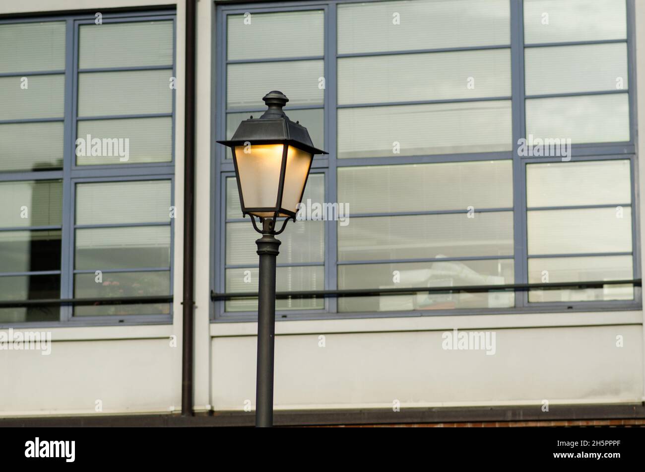 Beleuchtete Laternenpfosten vor dem Hintergrund der Fenster eines modernen Gebäudes in der Metropole. Stockfoto