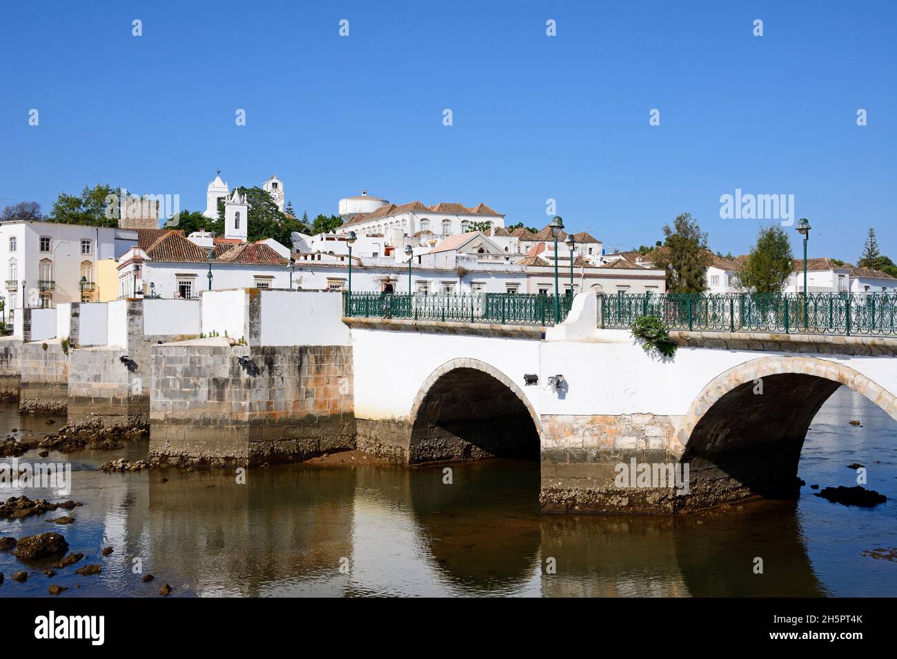 Blick auf die römische Brücke (Ponte Romano) und den Fluss Gilao mit Stadt Gebäude an der Rückseite, Tavira, Algarve, Portugal, Europa. Stockfoto