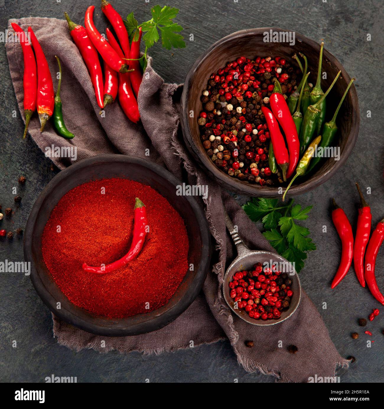 Rote Chili oder Chili Cayennepfeffer und Pfefferkörner auf dunklem Hintergrund. Traditionelles Gewürzkonzept. Draufsicht, flach liegend, Kopierbereich Stockfoto