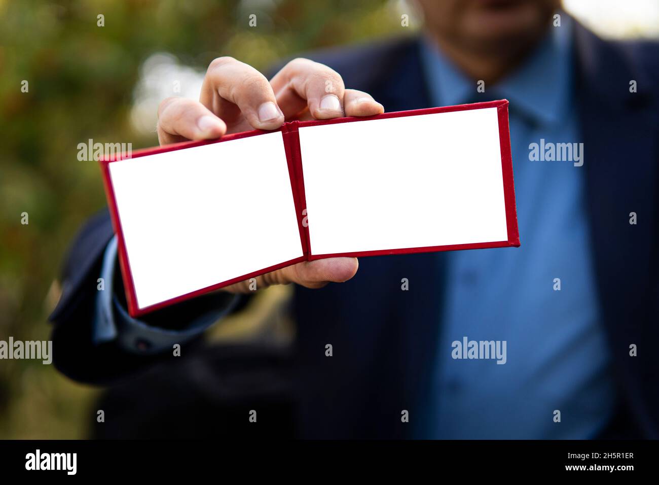 Ein Geschäftsmann in einem schwarzen Anzug zeigt seinen Personalausweis. Ein Beamter mit hohem Status zeigt sein rotes Dokument. Parlamentarische Immunität, leerer Personalausweis für tes Stockfoto