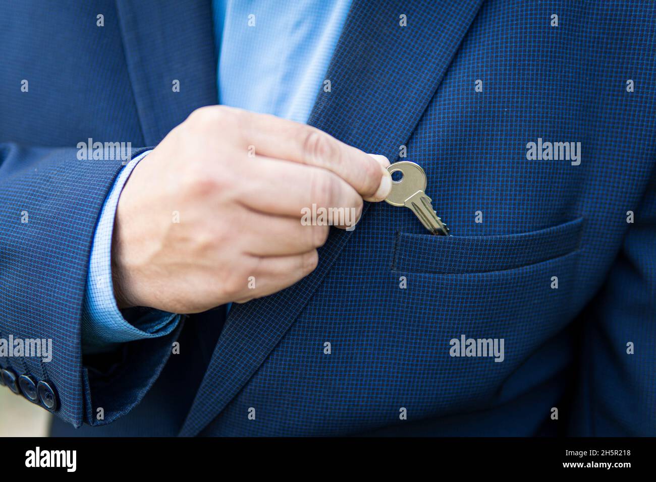 Immobilientransaktionen. Der Immobilienmakler. Das Konzept des Privateigentums. Geschäftsmann in einem Business-Anzug mit privatem Hausschlüssel in der Tasche. Stockfoto