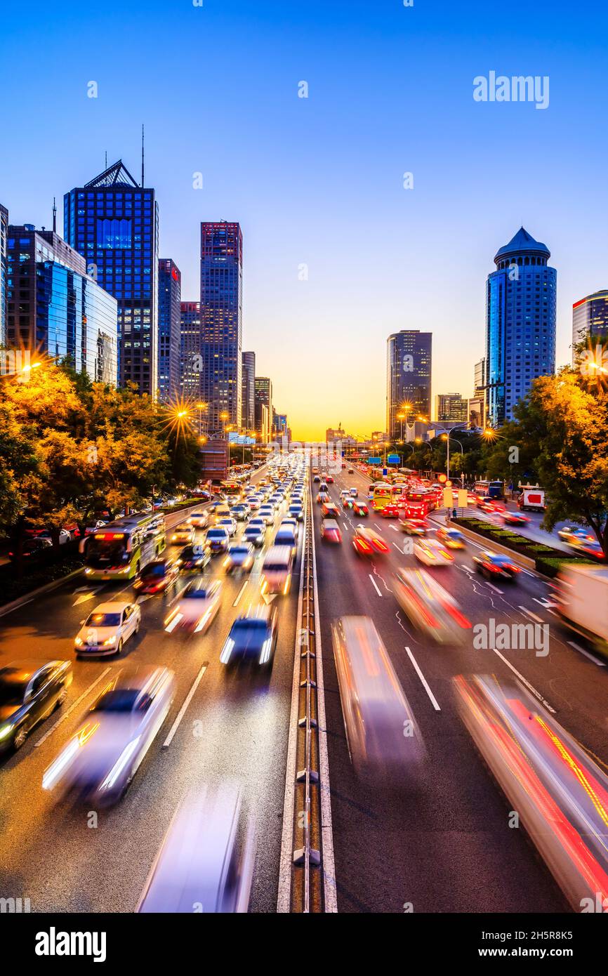 Belebte Stadtstraße und Wolkenkratzer in Peking bei Nacht, China. Stockfoto
