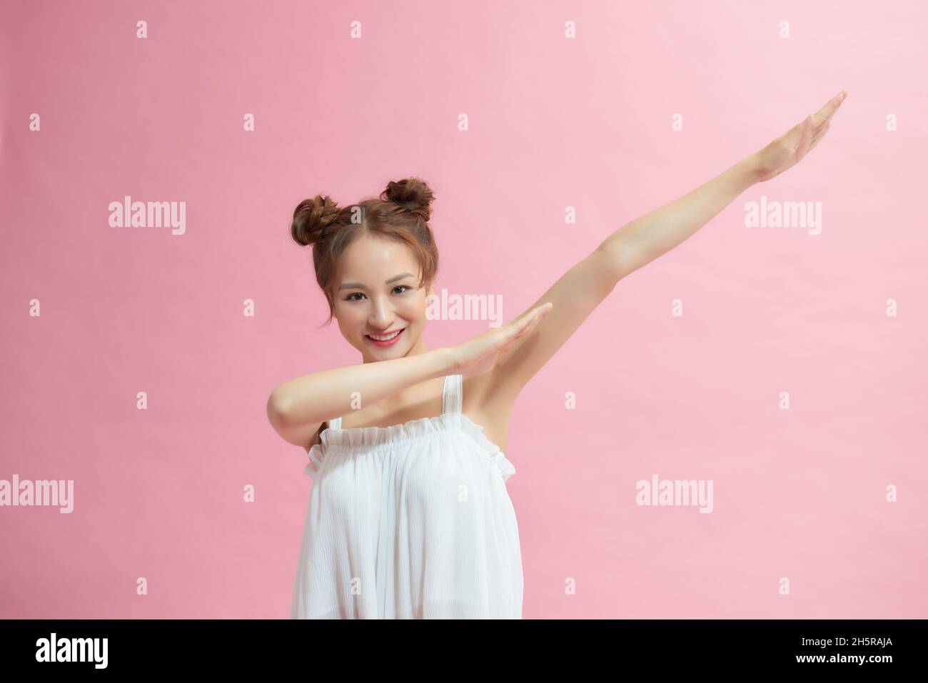 Fröhliche lustige junge Frau 20er Jahre tun DAB Hip Hop Tanz Hände Geste, auf pastellrosa Hintergrund Studio-Porträt Stockfoto