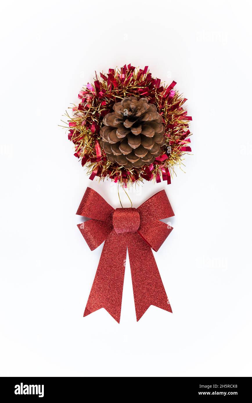 Schöne rote Schleife Geschenk mit Pinecone Blume über Lametta weihnachtsdekoration isoliert auf weißem Hintergrund. Weihnachtsschmuck mit traditionellem Kieferkegel A Stockfoto
