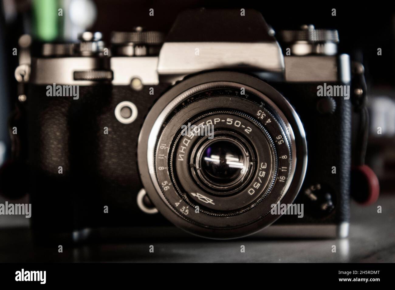 Detail eines alten 50mm USSR-Objektivs im Retro-Stil auf einem silbernen und schwarzen Hybrid-Kameragehäuse auf einem grauen Schreibtisch Stockfoto