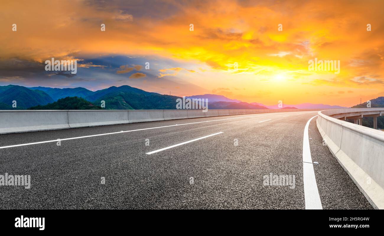 Asphaltstraße und grüne Berglandschaft bei Sonnenuntergang. Stockfoto