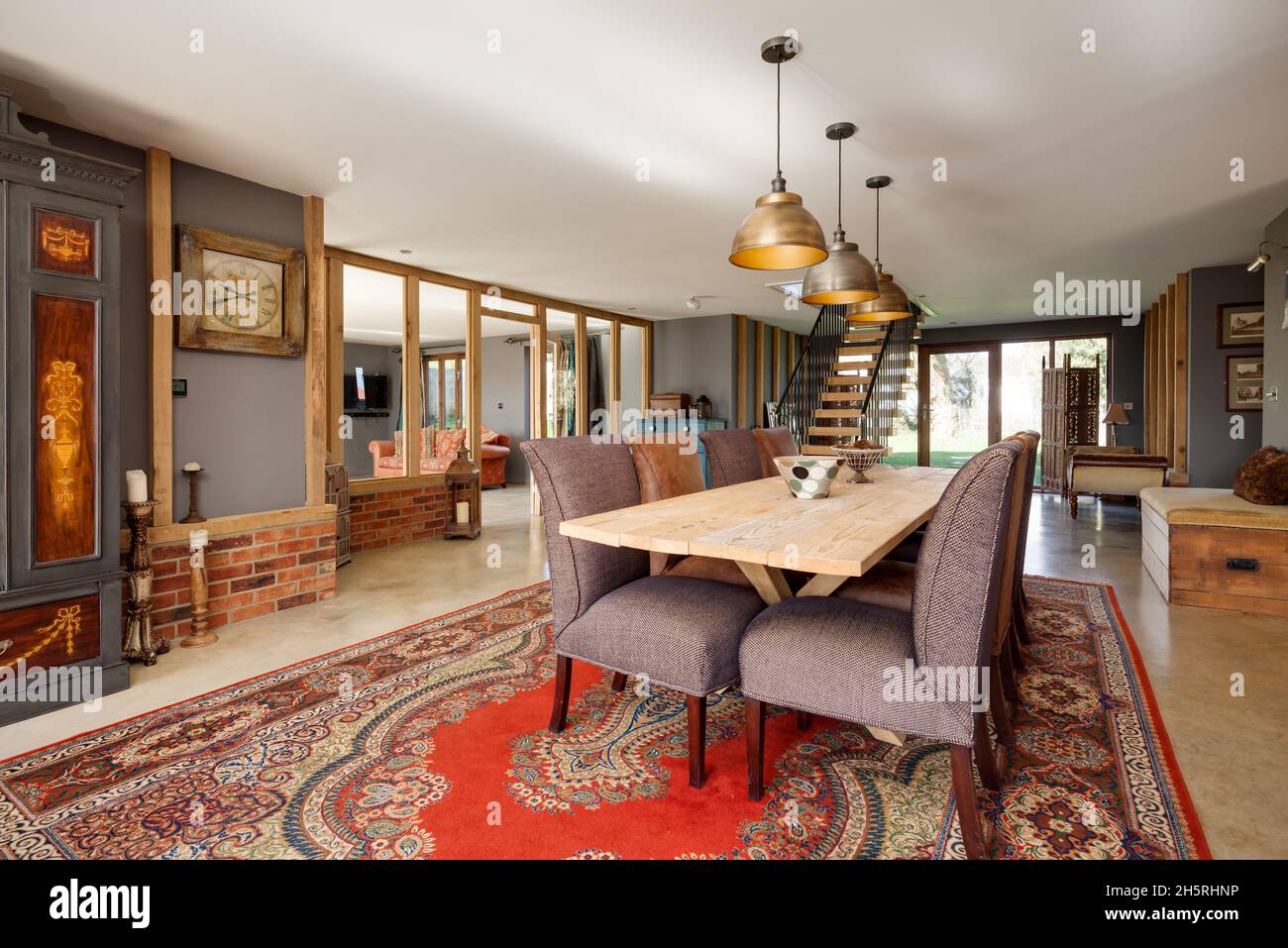 Suffolk, England - März 2018: Speisesaal in umgebauter Scheune dominiert von einem großen Esstisch mit acht Stühlen, die von Sonnenschein beleuchtet werden Stockfoto
