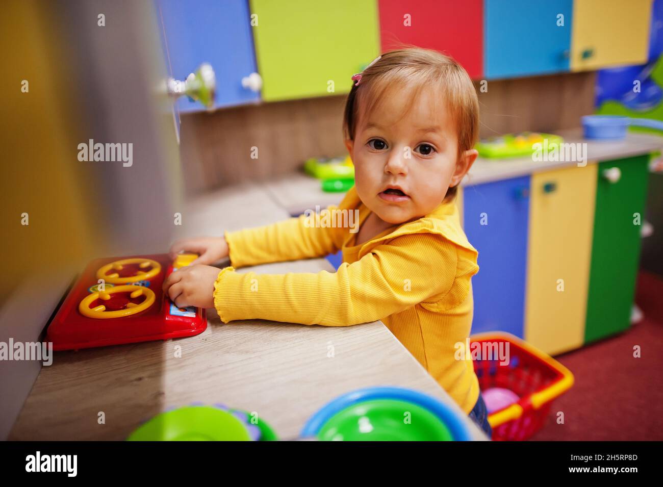 Nettes Baby Mädchen spielen in Indoor-Play-Center. Kindergarten oder Kindergarten Spielzimmer. Bereitet Essen auf dem Herd in der Kinderküche zu. Stockfoto