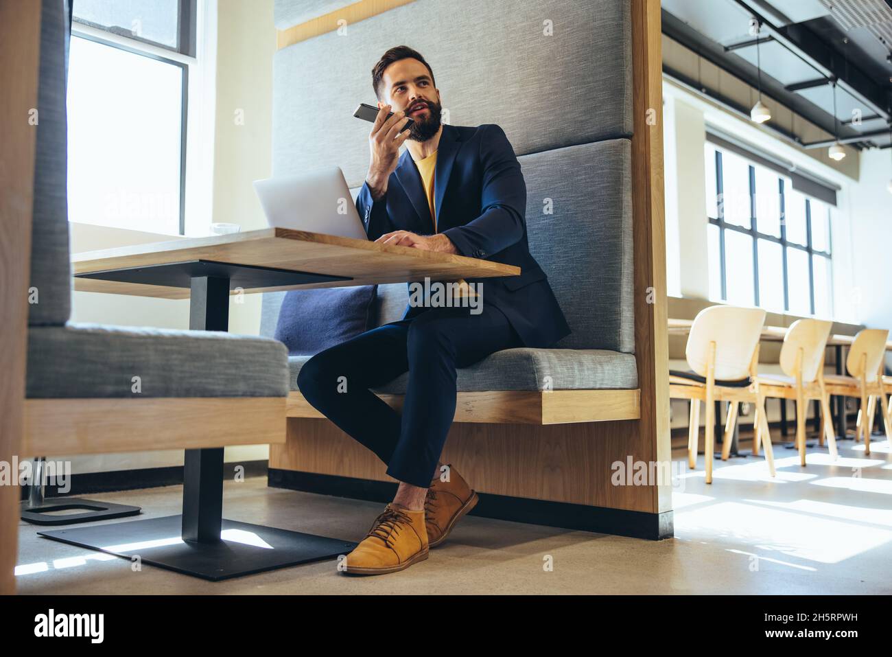 Geschäftsmann, der telefoniert. Zielgerichteter junger Geschäftsmann, der mit seinen Geschäftspartnern am Telefon kommuniziert. Junger Unternehmer Stockfoto