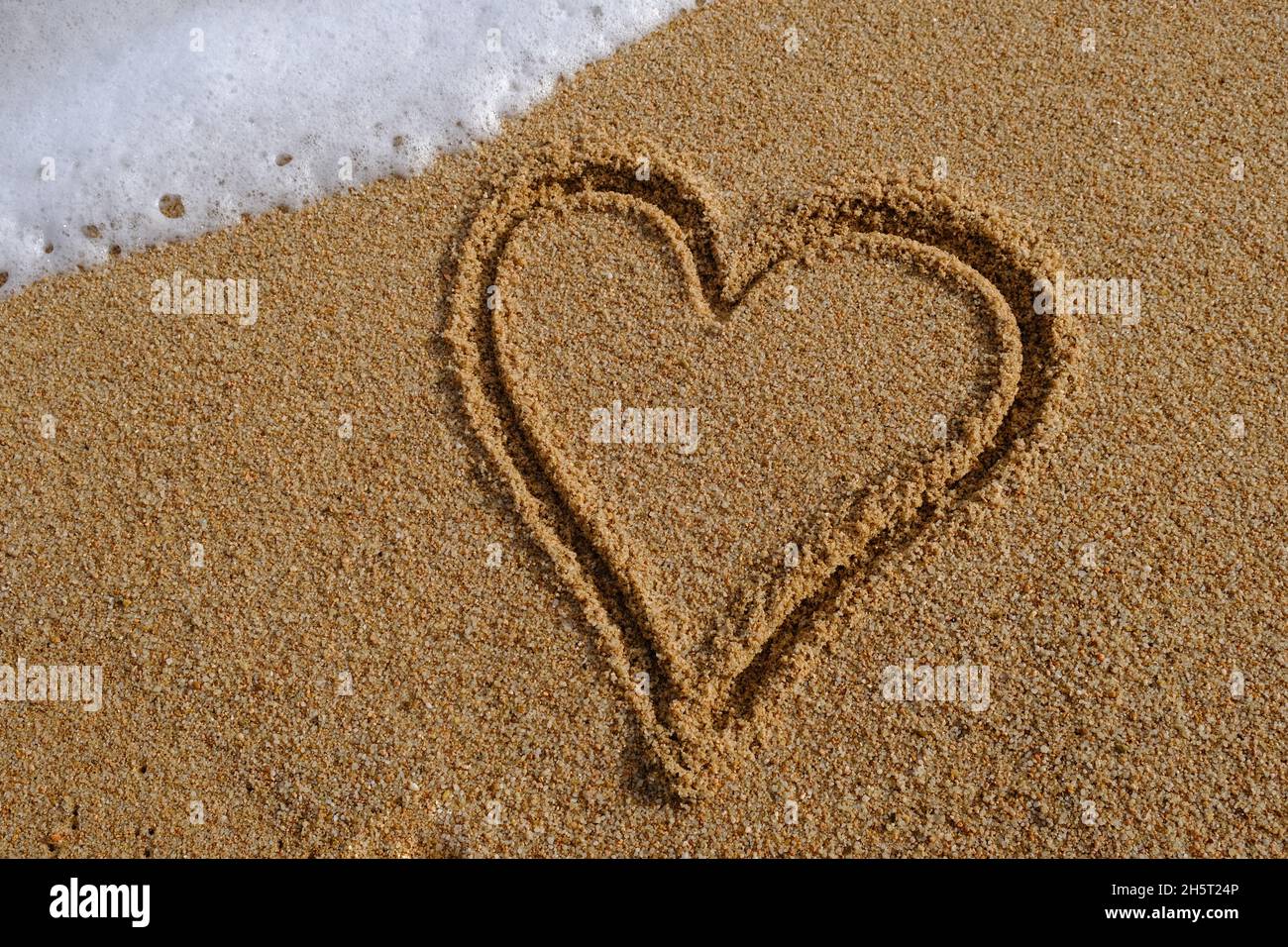 Herzzeichen auf Sand in Abendsonne geschrieben Stockfoto