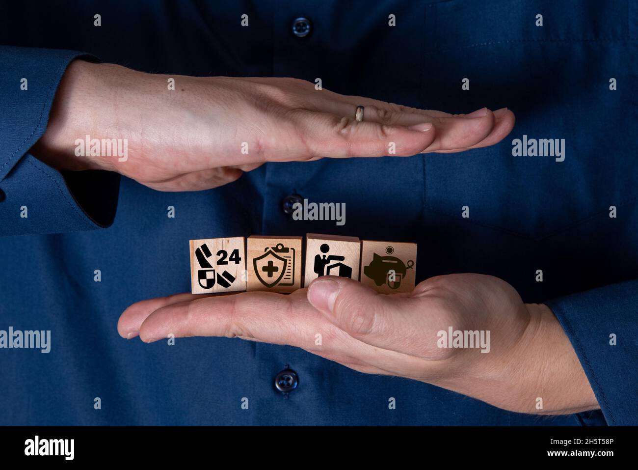 Die Hand hält Holzwürfel mit Versicherungssymbolen. Das Konzept der Lebensversicherung und Medizin. Stockfoto