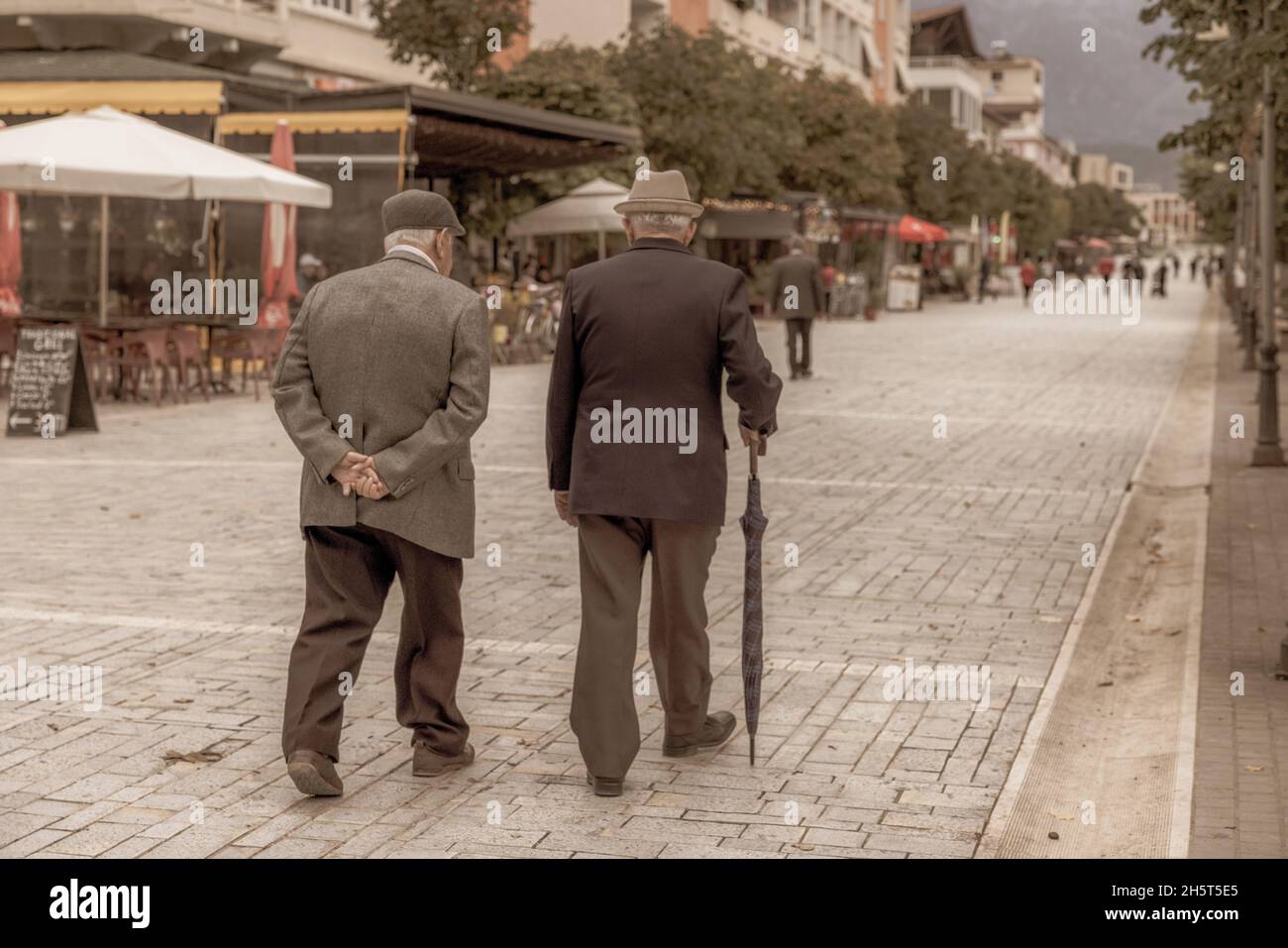 Foto im Vintage-Stil von zwei elegant gekleideten älteren Herren bei einem Spaziergang am frühen Abend in berat albanien Stockfoto