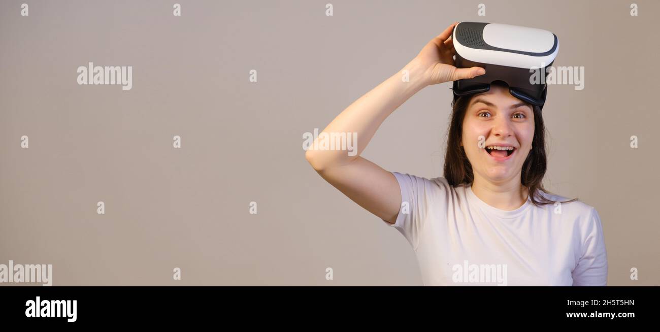 Eine Frau zieht die Virtual-Reality-Brille aus und lacht, wenn sie die Kamera anschaut. Stockfoto