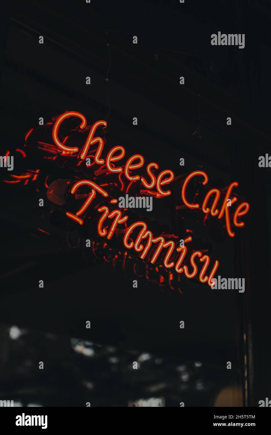 Neonzeichen „ Tiramisu und Käsekuchen “. Leuchtendes rotes Neonschild im Café-Interieur Stockfoto