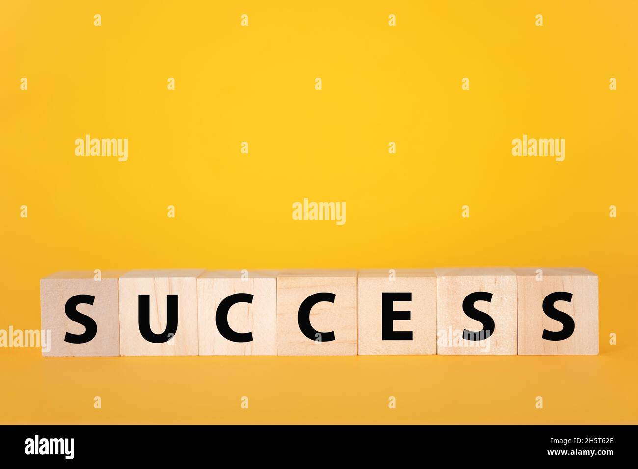 Der Erfolg des Textes auf einem gelben Hintergrund aus Holzwürfeln. Geschäftswachstum in der Teamarbeit. Stockfoto