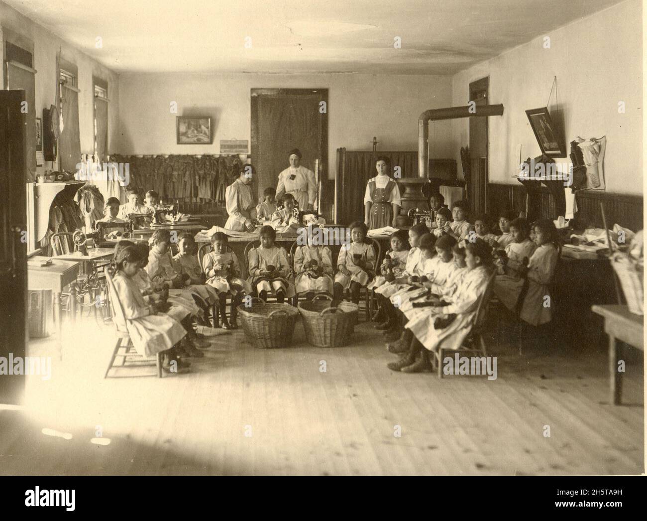 Blick auf indische Mädchen, die an der Albuquerque Indian School, Ende der 1890er oder Anfang der 1900er Jahre, zum Nähen unterrichtet werden. Stockfoto