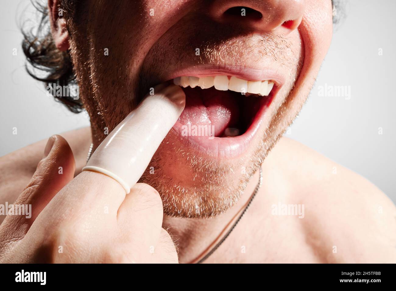Mann mit Finger im Mund, der Zähne zeigt Stockfoto