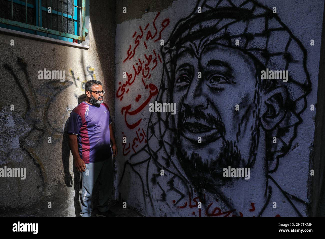 Palästinenser in der Nähe eines Wandbildes, das den verstorbenen palästinensischen Führer Yasser Arafat am 11. November 2021 in Rafah im südlichen Gazastreifen zeigt. Stockfoto